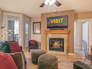 A living room with a fireplace, a television displaying 'VISIT WINTER PARK,' and a door leading to another room.