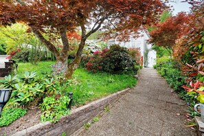 A pathway leading to a building surrounded by lush greenery and various plants.