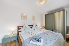 A neatly made bed with pillows, a bedside table with a lamp, and a chair.