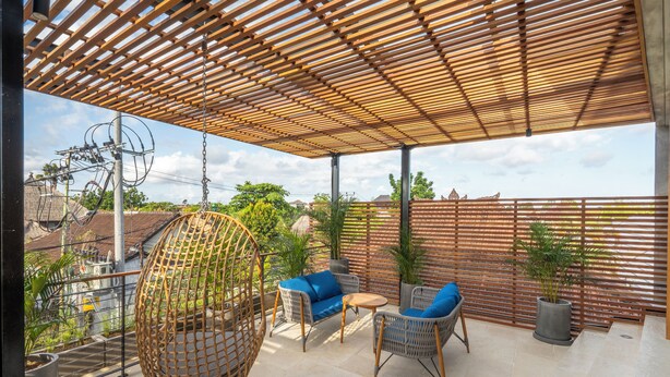 A covered patio with wicker furniture, a hanging chair, and potted plants. - Deluxe 2-Bedroom Tropical Haven in Seminyak with Pool & Designer Interiors (Badung)
