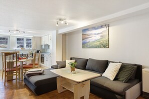 Een moderne woonruimte met een bank, een tafeltje en een eethoek met stoelen.