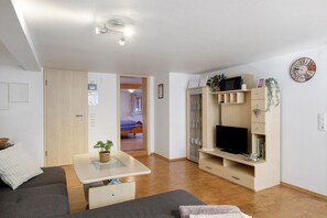 Una sala de estar moderna con un sofá, una mesita, un televisor y una estantería.