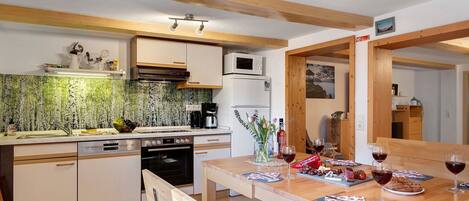 A kitchen with wooden cabinets, a microwave, and a dining area with a table set for two.