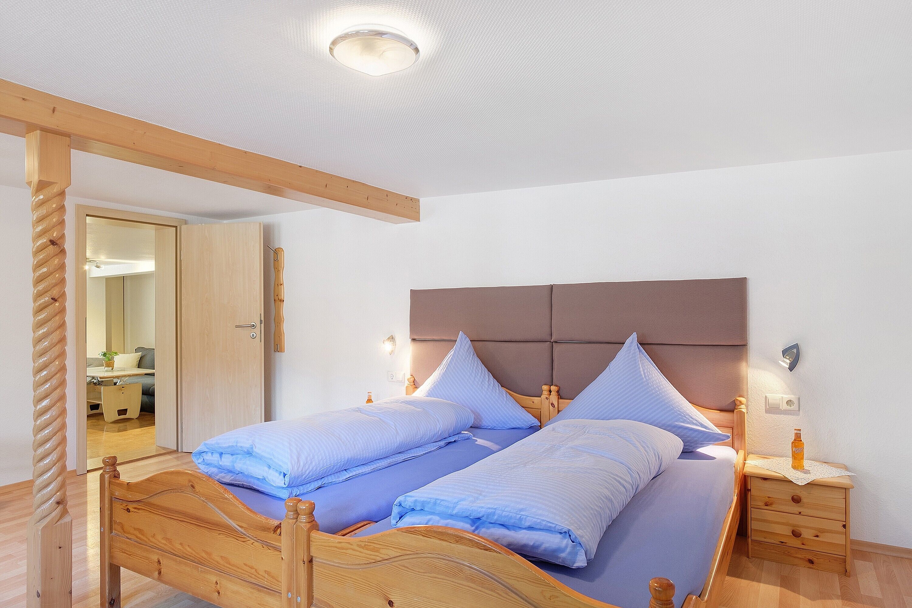 Ein Doppelbett mit Holz Kopfteil, zwei Nachttische mit Lampen und ein Holzboden.