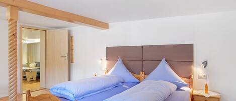 Ein Doppelbett mit Holz Kopfteil, zwei Nachttische mit Lampen und ein Holzboden.