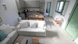 A modern living room with a sofa, coffee table, and a dining area with a table and chairs. - Newly built detached house, private pool, sea views, Aegina, 400m from the beach (Aegina Agioi)