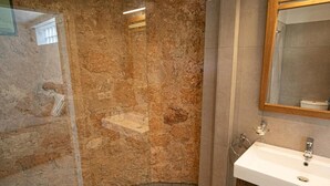 A bathroom with a stone wall, a white sink, and a mirror. - Newly built detached house, private pool, sea views, Aegina, 400m from the beach (Aegina Agioi)