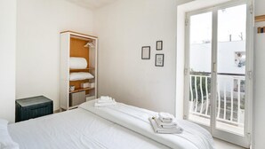 A hotel room with a bed, a wardrobe, a small table, and a balcony with a railing. - Porto Marina by Rentbeat (Villanova di Ostuni)
