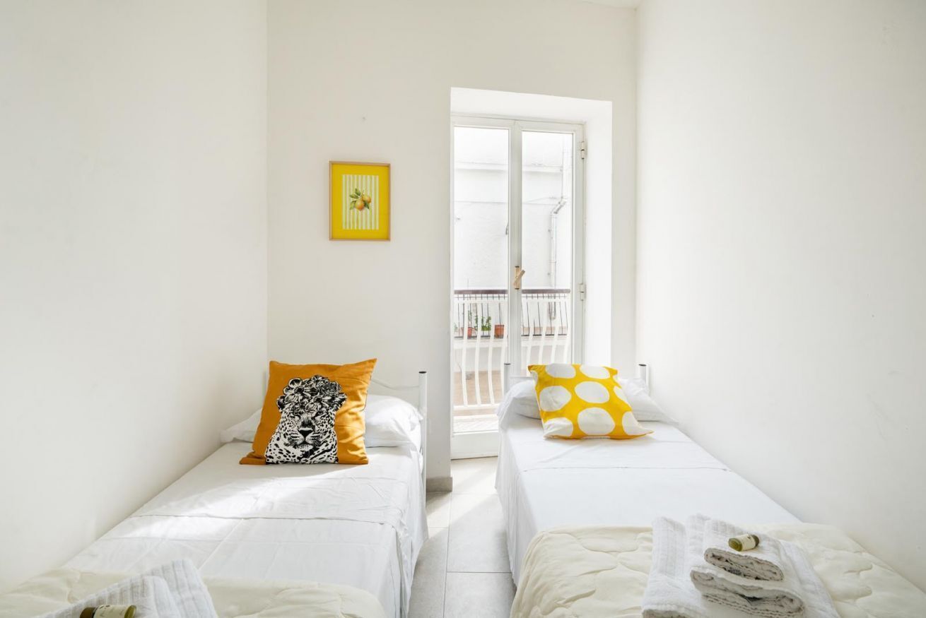 Habitació amb dos llits, un balcó i un quadre amb el marc groc.