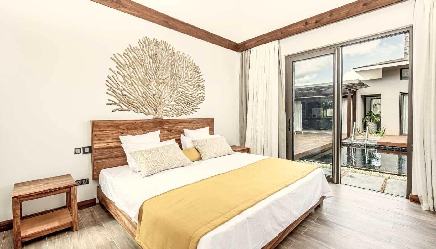 A bedroom with a large bed, wooden headboard, and a view of a pool through a sliding glass door.