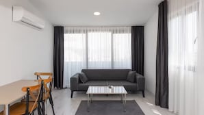 A modern living room with a sofa, a coffee table, a dining table with chairs, and an air conditioning unit. - Moon Old Town (Antalya)