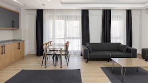 A modern living room with a grey sofa, a dining table with chairs, and a kitchen area with wooden cabinets. - Moon Old Town (Antalya)