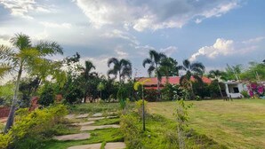 A garden with a pathway leading to a building with a red roof. - The Palash Vann Resort (Kurai)