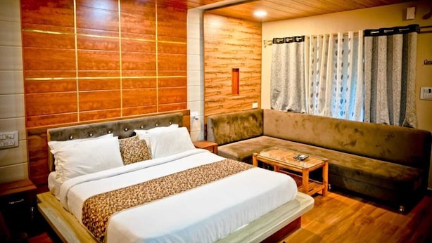 A hotel room with a wooden ceiling, a large bed with white bedding, a sofa, and a small table. - The Palash Vann Resort (Kurai)