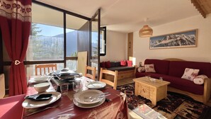 Un coin repas avec une table dressée pour deux personnes, un canapé et un tableau accroché au mur.