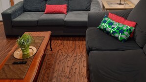 Una sala moderna con un sofá gris, una mesa de centro de madera y una planta pequeña.