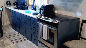 Una cocina moderna con armarios oscuros, horno integrado y cafetera.
