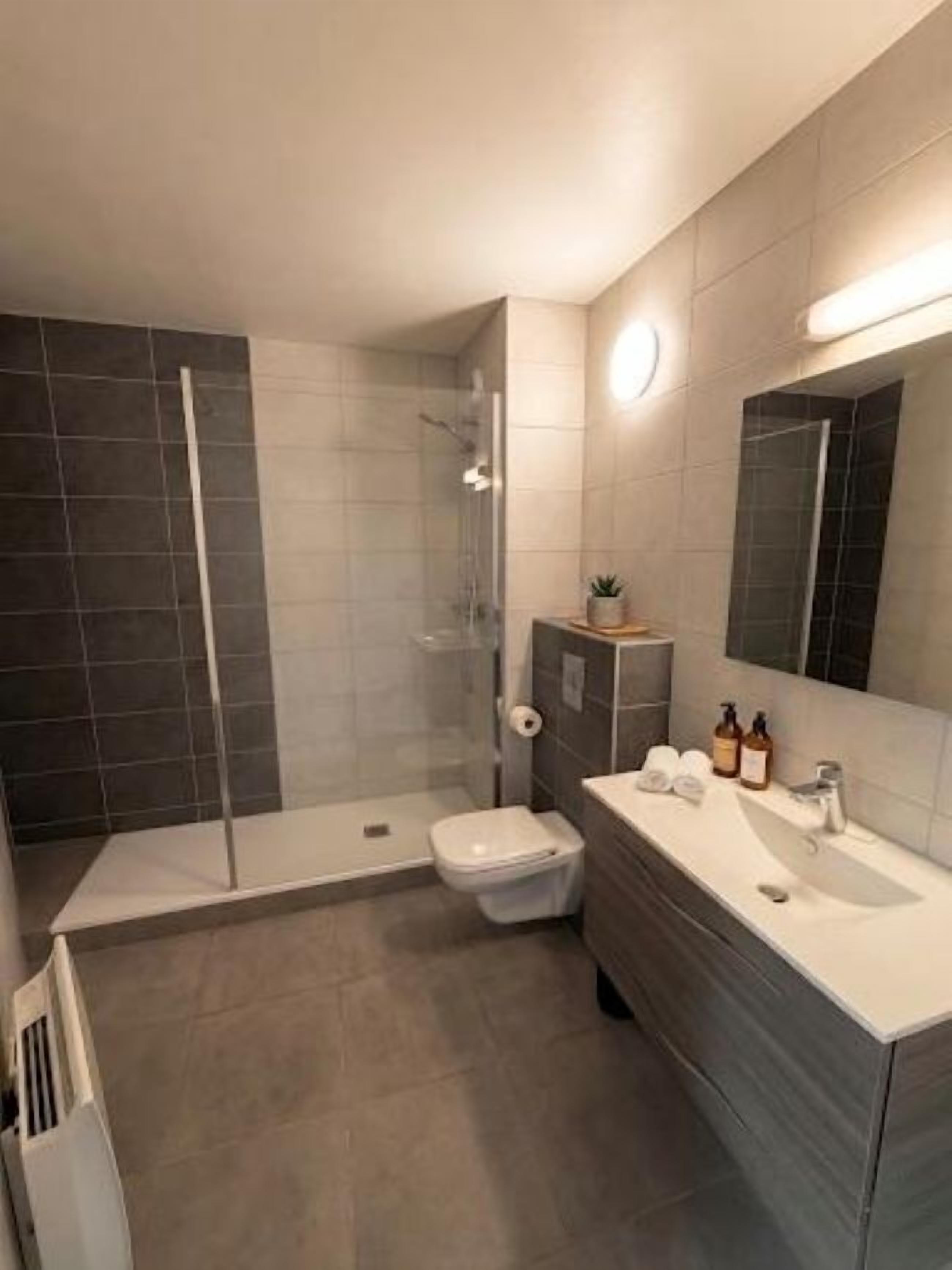 A modern bathroom with a shower, toilet, and vanity.