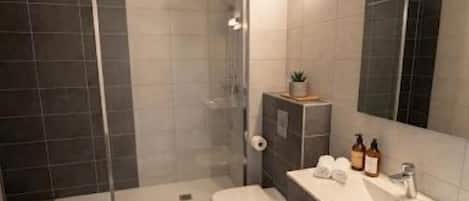 A modern bathroom with a shower, toilet, and vanity.