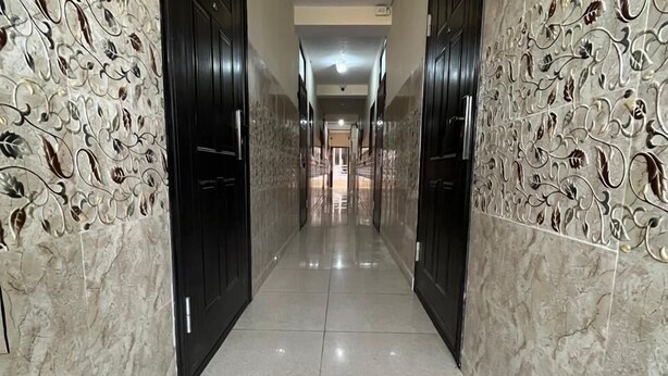 A hallway with marble walls and doors, leading to a bright room. - The Harikanta Residency (New Delhi)