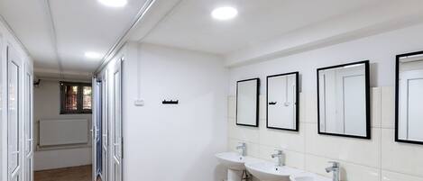 A modern bathroom with three sinks, a window, and a radiator.