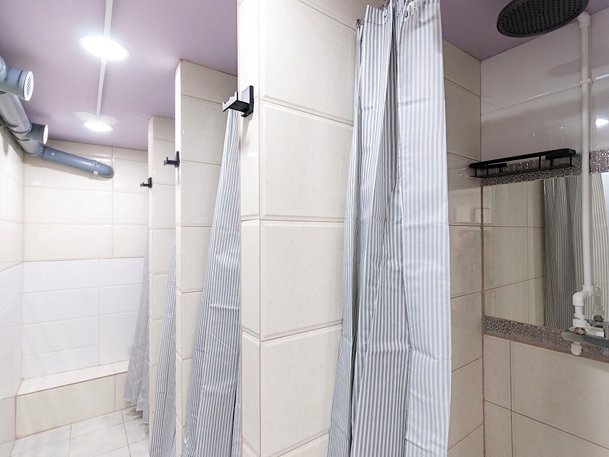 Une salle de bain moderne dotée d’une zone de douche, de murs carrelés et d’un miroir orné d’un cadre décoratif.