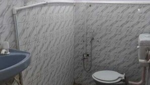A small bathroom with a sink, toilet, and shower. The floor has a patterned tile design. - Hotel Sita Kunwar (Prayagraj)