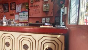 A reception area with a counter, framed pictures on the wall, and a potted plant. - Hotel Sita Kunwar (Prayagraj)