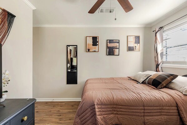 A bedroom with a bed, a dresser, a mirror, and three framed artworks on the wall. - Colorful and Cozy 2 Bedroom in Columbus (Columbus)