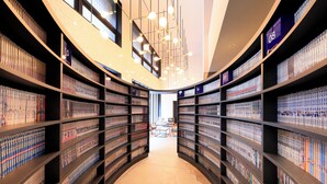 Une bibliothèque dont les étagères sont disposées en arc de cercle, avec un espace de lecture central et un plafond au design moderne.