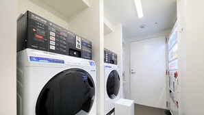 Une buanderie équipée de deux machines à laver à chargement frontal et d’un panneau de commande placé au-dessus.