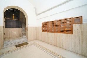 Un couloir doté d’un sol en marbre, d’un banc en bois et d’un meuble de rangement mural comportant plusieurs compartiments.