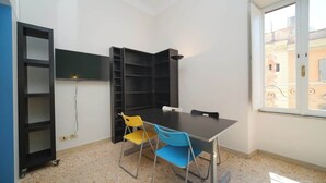 A room with a table, chairs, a bookshelf, and a window.