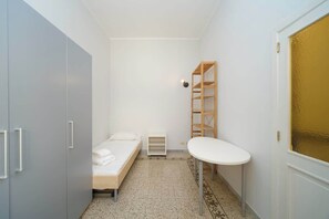 A small, compact room with a single bed, a white table, a wardrobe, and a shelf unit. - BuddyRent - San Lorenzo - Roma - 5 ospiti (Roma)