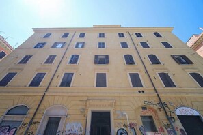 A multi-story building with a yellow facade, multiple windows, and a door with signage.