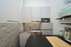 A compact kitchen with a gas stove, a microwave, and a refrigerator.