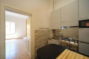 A kitchen with a gas stove, stainless steel appliances, and a black countertop.