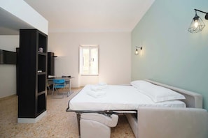 Ein Schlafzimmer mit einem Bett, einem Schreibtisch, einem Stuhl und einem Bücherregal.