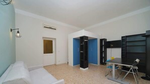 A room with a white sofa, a table with chairs, a blue cabinet, and a door.