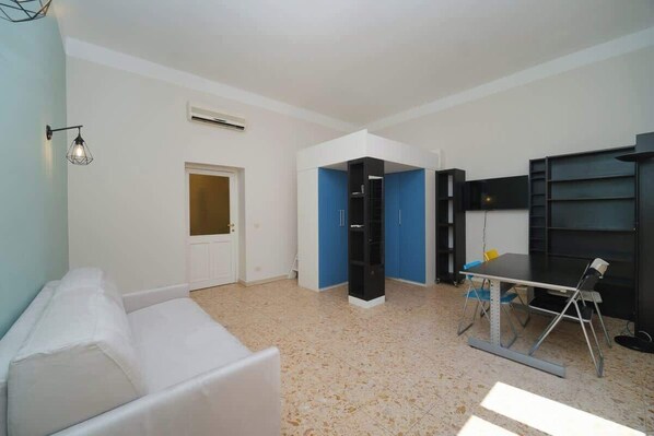 A room with a white sofa, a table with chairs, a blue cabinet, and a door.