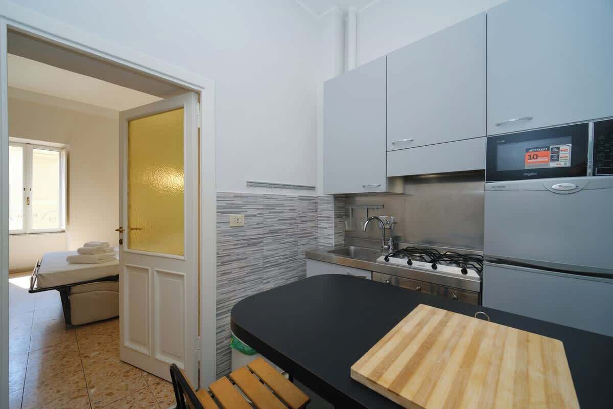 A modern kitchen with grey cabinets, a black countertop, and a stove.