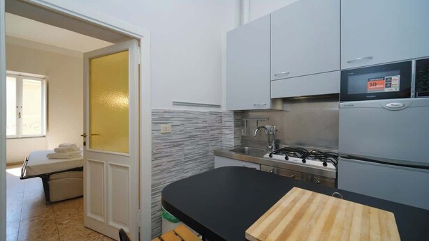 A modern kitchen with grey cabinets, a black countertop, and a stove.