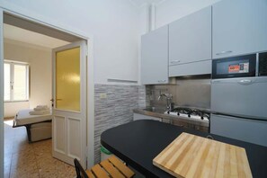 A modern kitchen with grey cabinets, a black countertop, and a stove.