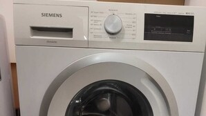 Een Siemens wasmachine met voorlader, voorzien van een digitaal bedieningspaneel en een grote deur van roestvrij staal.