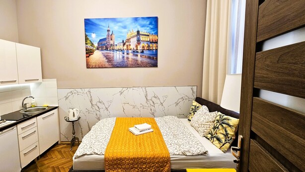 Een compacte hotelkamer met een bed, een magnetron, een wastafel en een klein tafeltje.