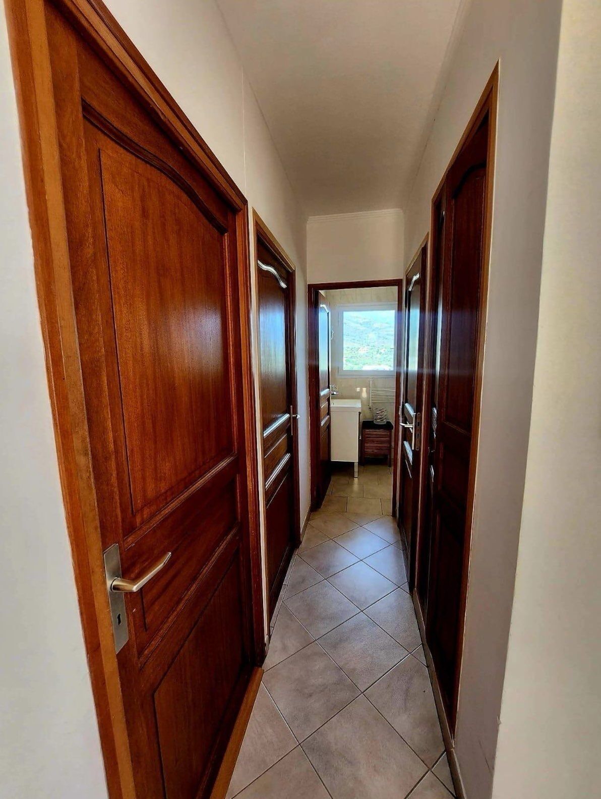 A hallway with wooden doors leading to a kitchen area.