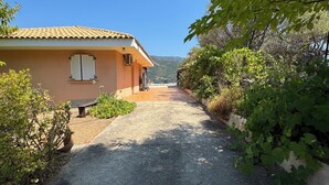 A paved driveway leading to a building with a tiled roof and a window with shutters. - Villas with swimming pool Sagone (Vico)