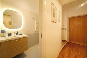 A bathroom with a vanity, mirror, and a wooden door.