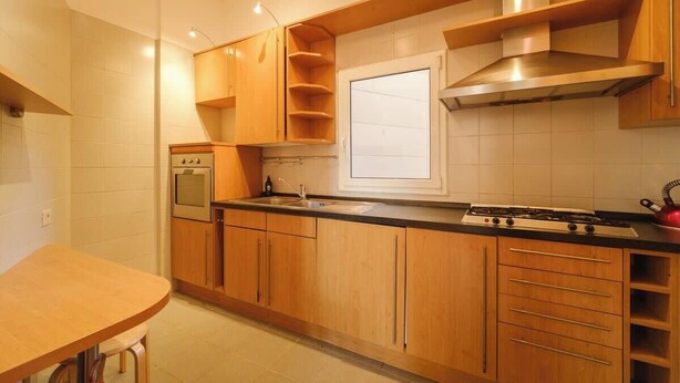A modern kitchen with wooden cabinets, a gas stove, a built-in oven, and a window above the sink.