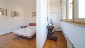 A bedroom with a bed, a bedside table, a lamp, and a window.